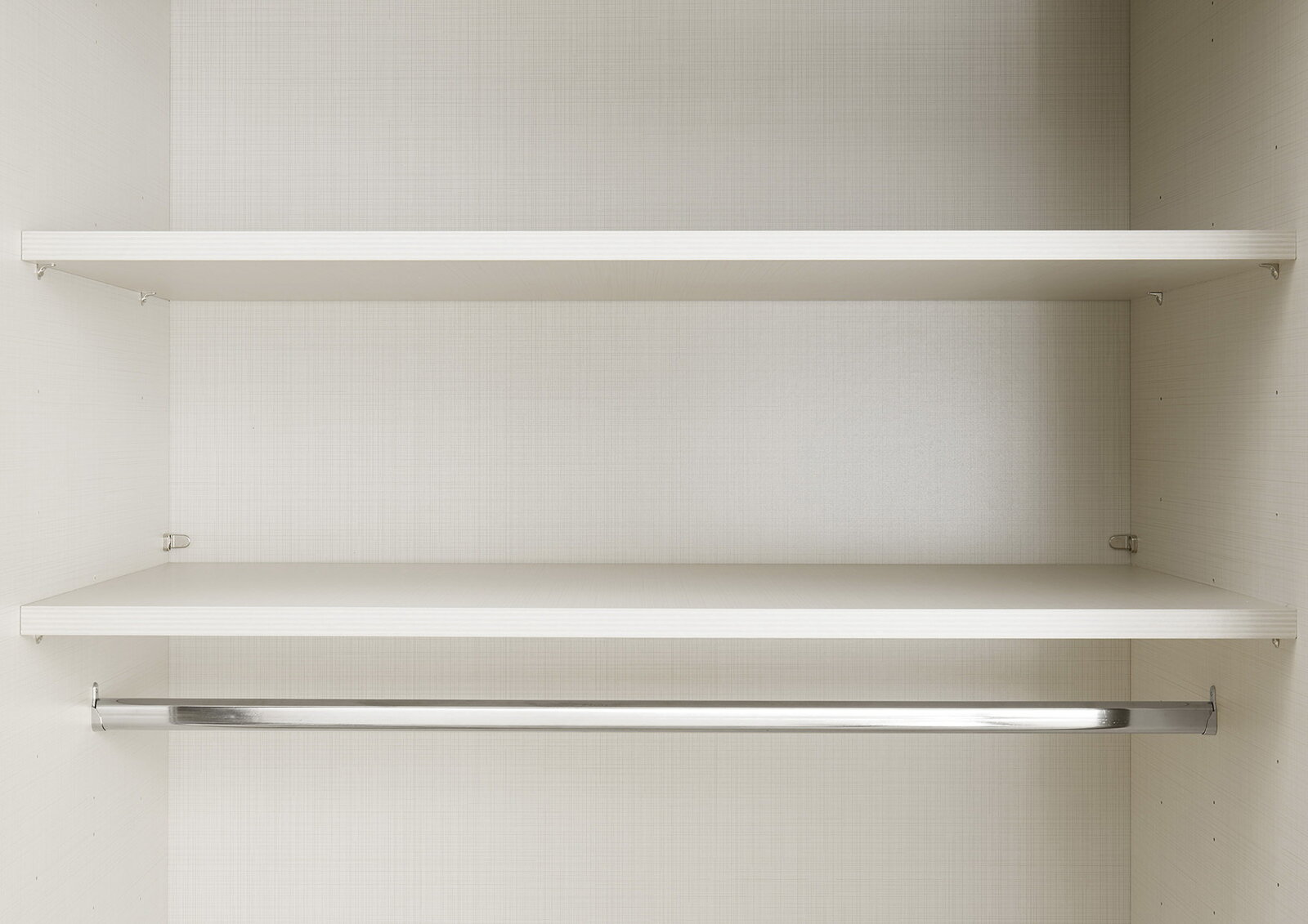 Innenansicht eines Schwebetürenschranks mit zwei Regalböden und einer Kleiderstange, frontal betrachtet.