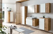 Moderner Hochschrank in Holzoptik mit weißen Fronten, Teil eines stilvollen Badezimmersets, aus seitlicher Perspektive fotografiert.