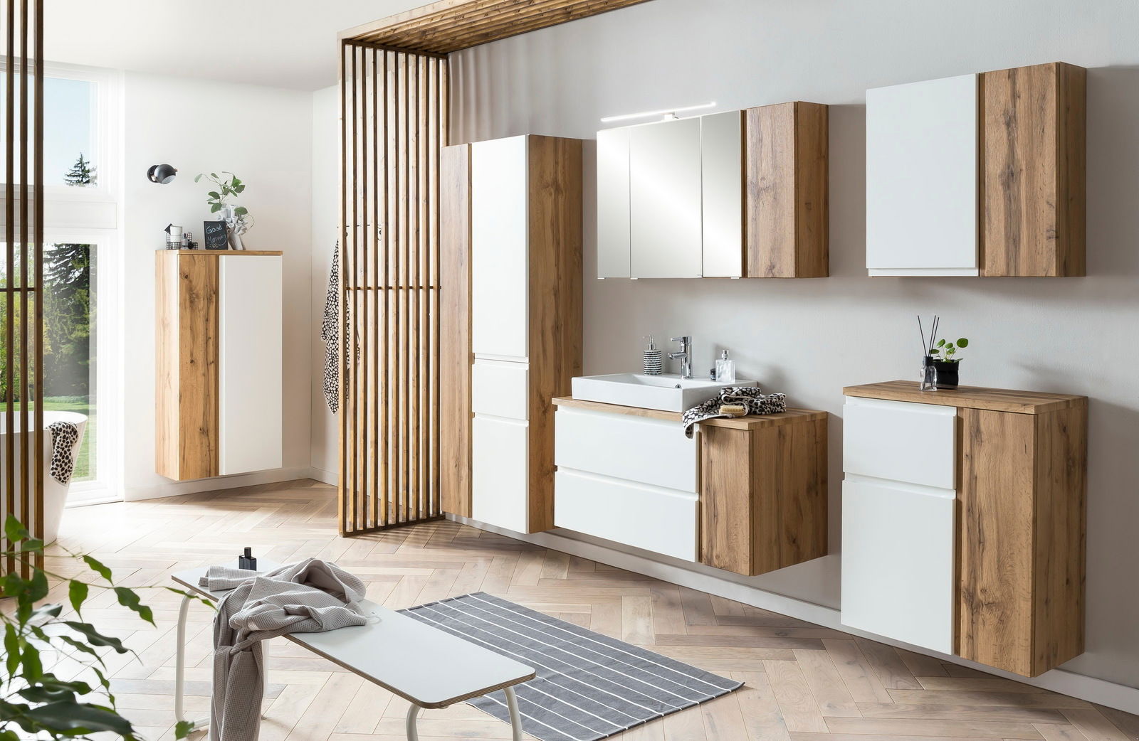 Moderner Hochschrank in Holzoptik mit weißen Fronten, Teil eines stilvollen Badezimmersets, aus seitlicher Perspektive fotografiert.