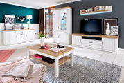 Helles Wohnzimmer-Set im Landhausstil mit weißer Anrichte, Vitrine, TV-Lowboard und Couchtisch in Weiß mit Holzoptik-Platten, frontal in leichter Weitwinkelperspektive fotografiert.