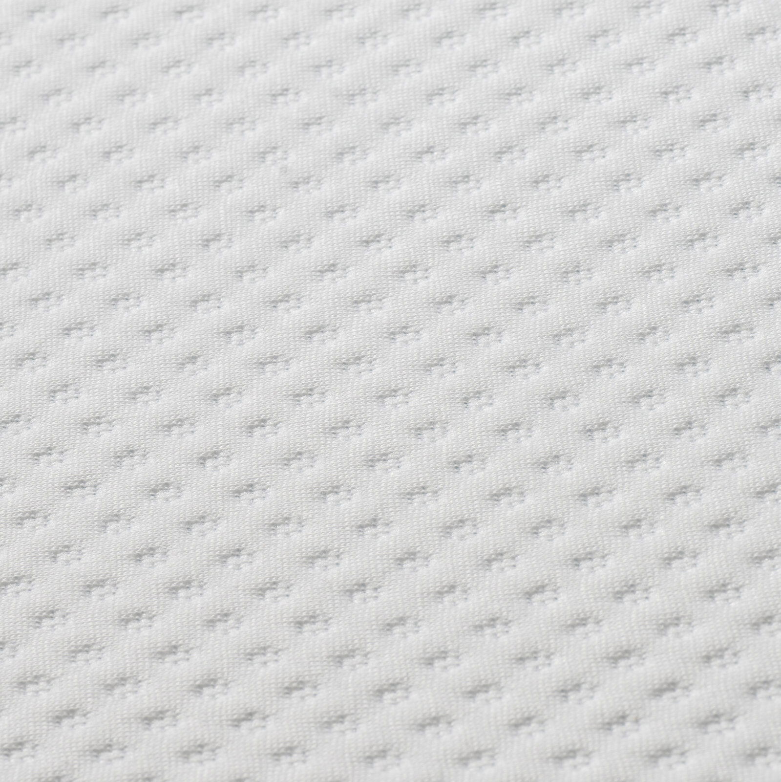 Nahaufnahme eines weißen, strukturierten Matratzentoppers in diagonaler Perspektive.