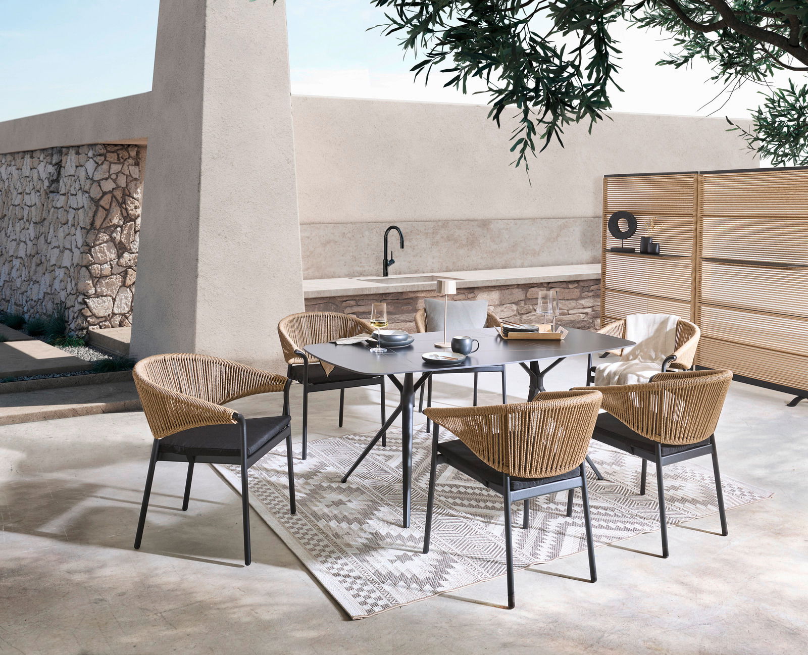 Dieter Knoll Gartentisch CELIA Moderne Gartenmöbelgarnitur mit einem rechteckigen Tisch und vier Stühlen aus Rattan, umgeben von einem Paravent, in einer stilvollen Außenumgebung. Perspektive von schräg oben.