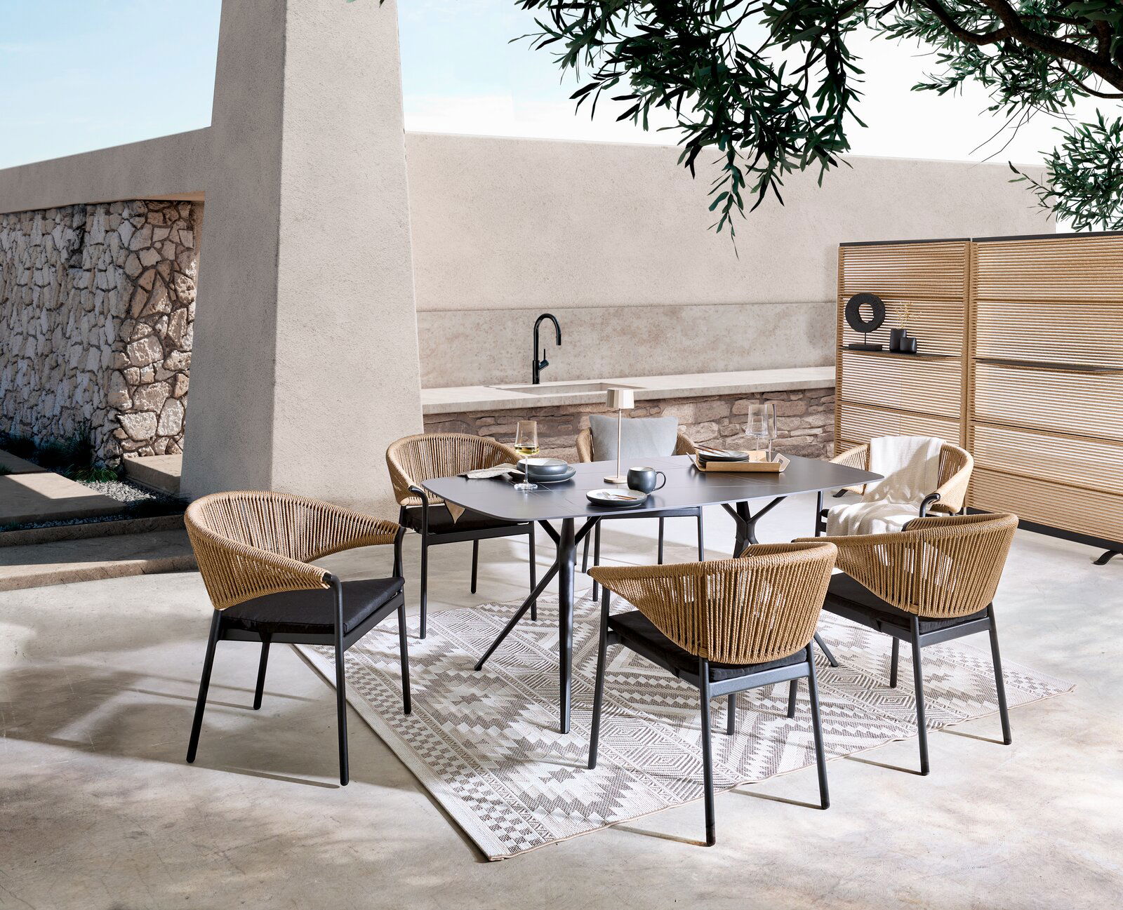 Dieter Knoll Gartentisch CELIA Moderne Gartenmöbelgarnitur mit einem rechteckigen Tisch und vier Stühlen aus Rattan, umgeben von einem Paravent, in einer stilvollen Außenumgebung. Perspektive von schräg oben.