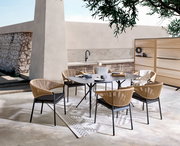 Moderne Gartenmöbelgarnitur mit einem rechteckigen Tisch und vier Stühlen aus Rattan, umgeben von einem Paravent, in einer stilvollen Außenumgebung. Perspektive von schräg oben.