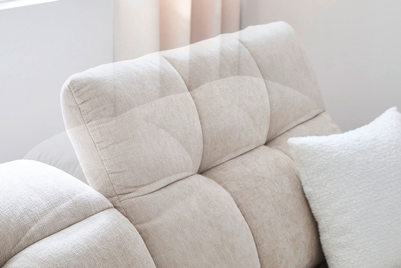 Nahaufnahme einer beigen Longchairkombination MARSEILLE mit weicher Polsterung und einem weißen Kissen, seitliche Perspektive.