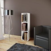 Weißes, schmales Schallplattenregal mit drei Fächern, gefüllt mit Vinyls, in moderner Wohnzimmerecke neben schwarzem Sofa und Stehlampe, Frontansicht in leichter Seitenperspektive.