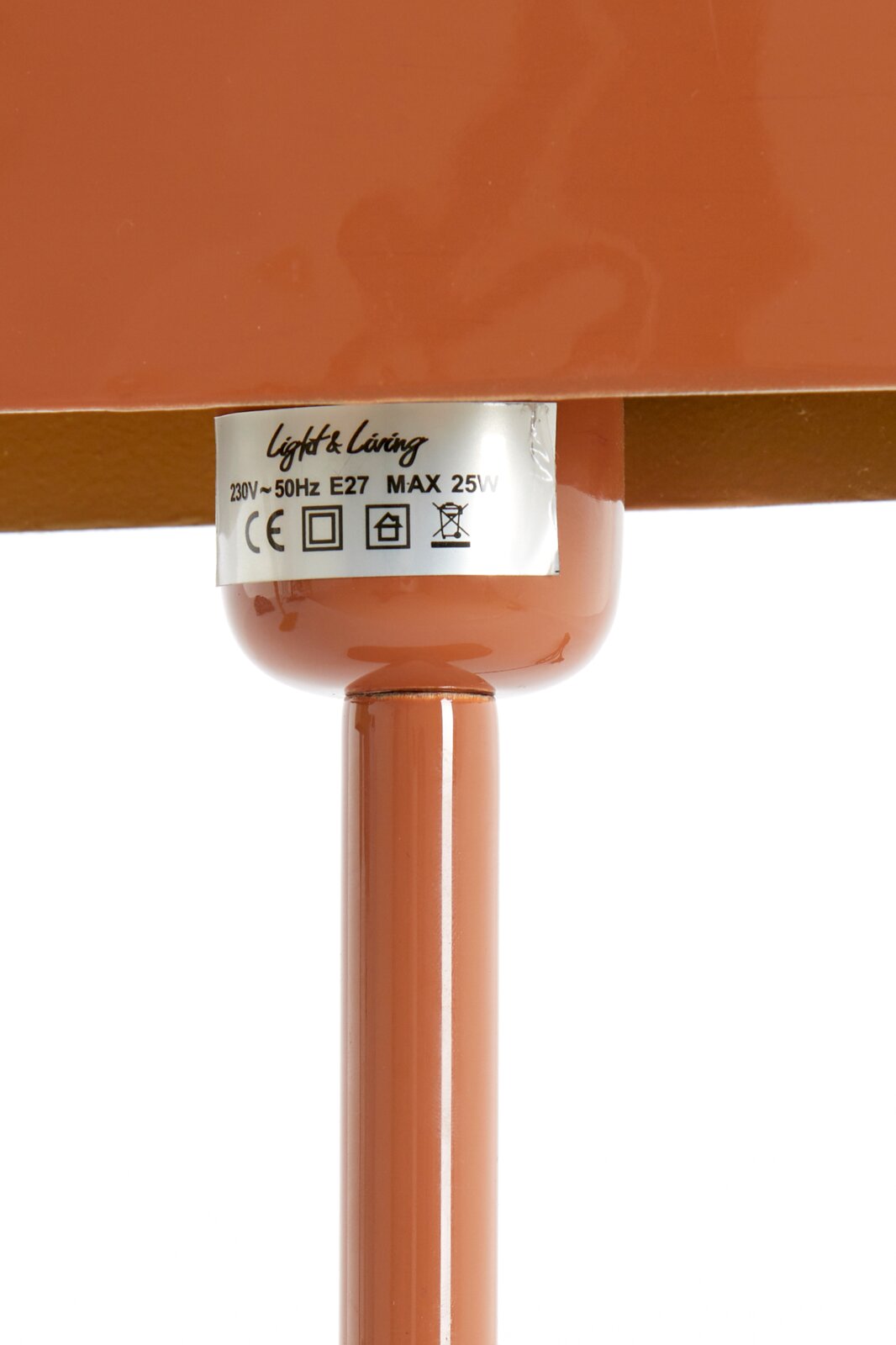 Nahaufnahme einer Tischleuchte in Terrakotta-Farbe mit einem Etikett, das technische Details zeigt. Perspektive von unten.