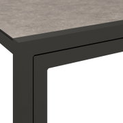 Detailansicht einer modernen Lounge-Bank mit grauer Tischplatte und schwarzem Metallrahmen.