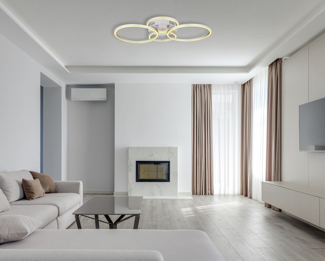 Moderne Deckenleuchte in Nickel matt mit drei leuchtenden Ringen, von unten betrachtet in einem stilvollen Wohnzimmer.