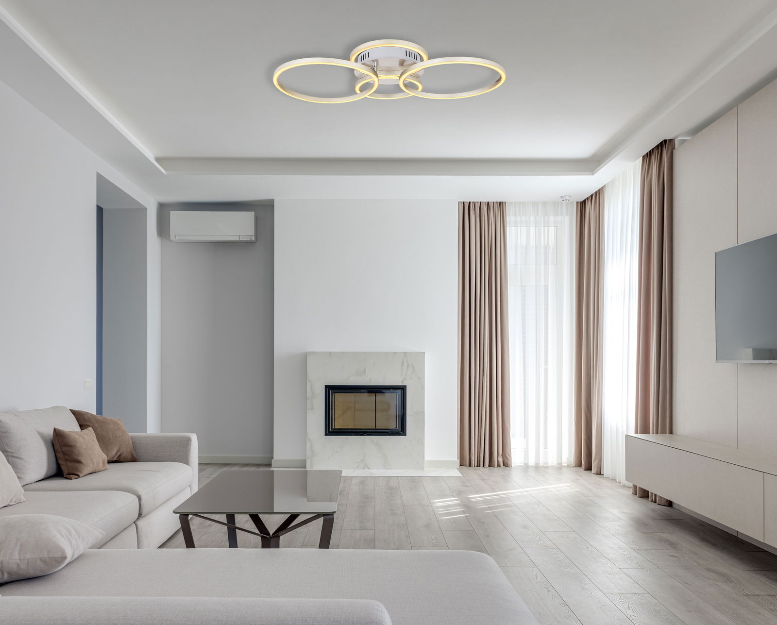 Moderne Deckenleuchte in Nickel matt mit drei leuchtenden Ringen, von unten betrachtet in einem stilvollen Wohnzimmer.