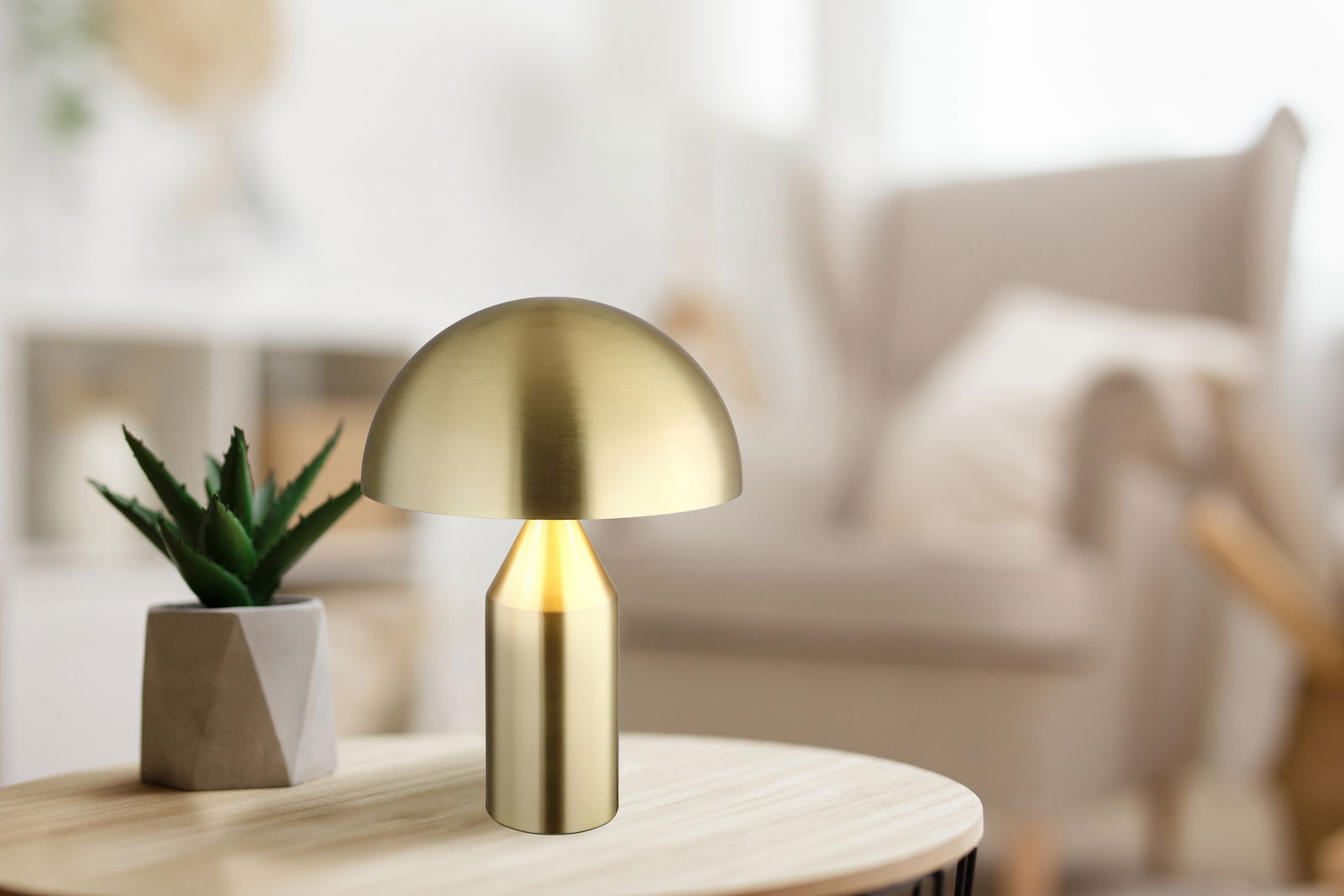 Moderne Tischleuchte ATOMA in Goldoptik auf einem Holztisch, seitliche Perspektive