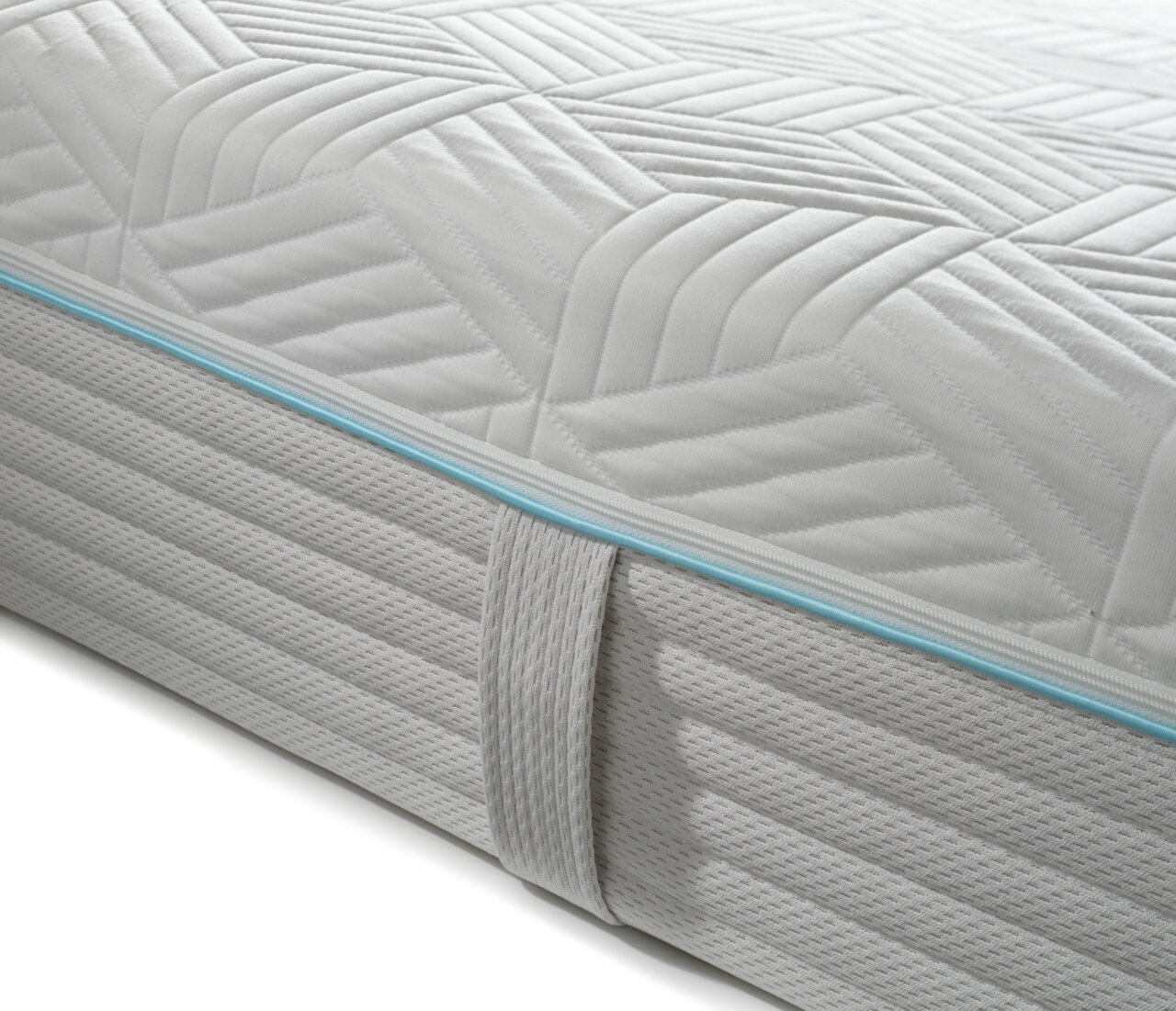 Nahaufnahme einer Gel-Kaltschaummatratze mit gestepptem Muster und blauer Zierleiste, seitliche Perspektive.