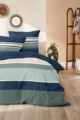 Bettwäsche-Set mit Streifenmuster in Blau- und Grüntönen, auf einem Bett in einem gemütlichen Schlafzimmer mit Holzboden und Dekorationen, aus der Vorderansicht fotografiert.