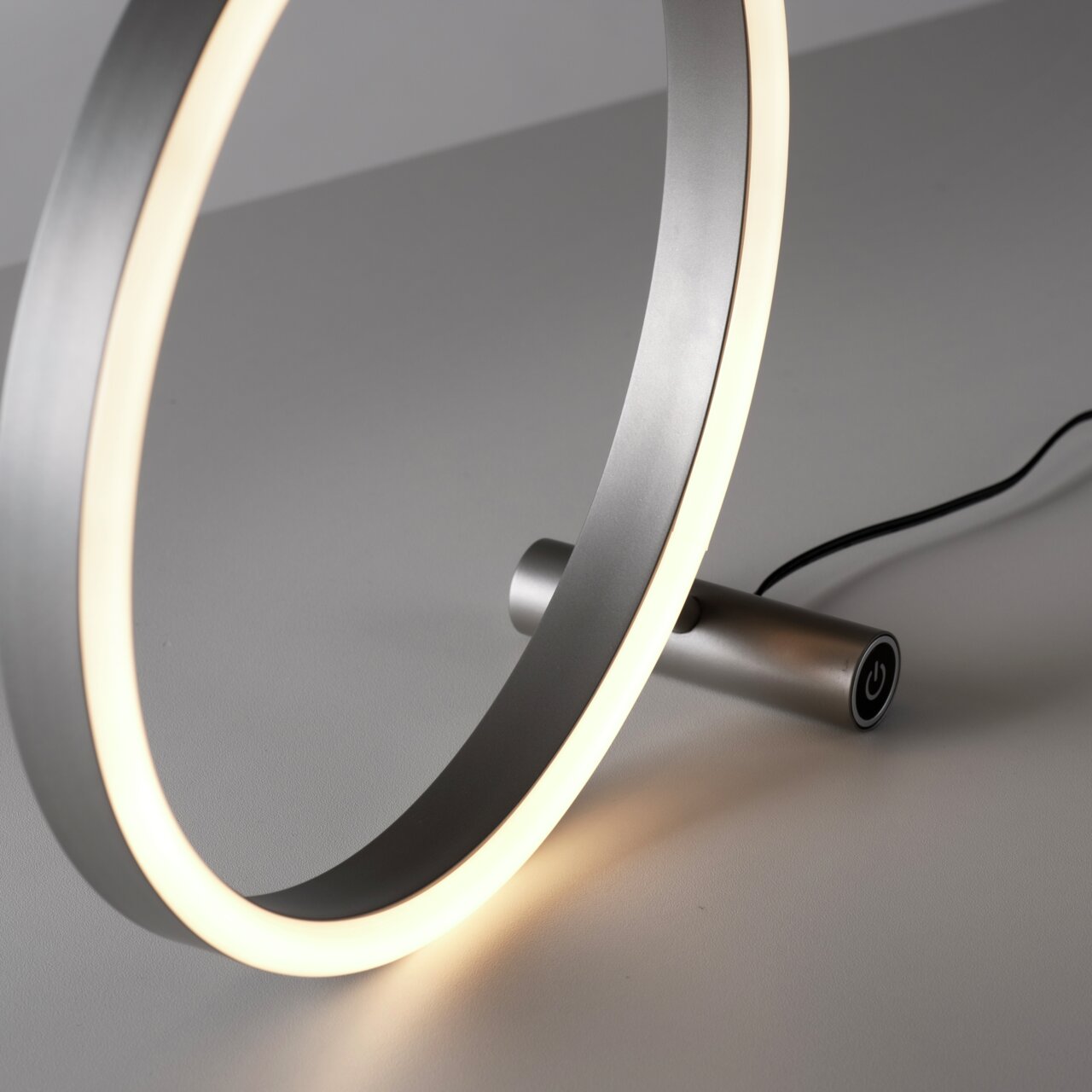 Moderne Tischleuchte RITUS in Ringform mit seitlicher Perspektive, leuchtend und mit Touch-Schalter.