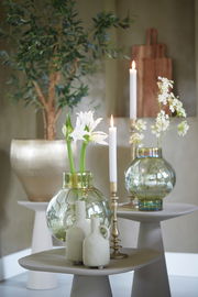 Dekorative Szene mit zwei Glasvasen der Serie DUSIT, gefüllt mit weißen Blumen, auf modernen Beistelltischen. Im Hintergrund ein großer Pflanzenkübel und ein Holzschneidebrett. Perspektive: seitlich von vorne.