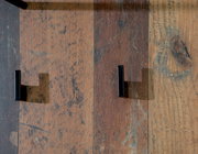 Nahaufnahme von zwei schwarzen Haken auf einer rustikalen Holzoberfläche, von oben betrachtet.