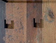 Nahaufnahme von zwei schwarzen Haken auf einer rustikalen Holzoberfläche, von oben betrachtet.