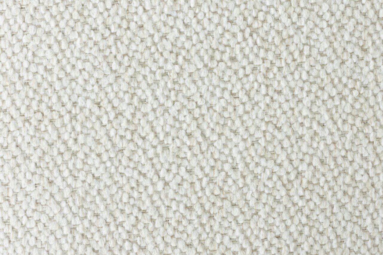 Nahaufnahme eines cremefarbenen Stoffes mit grober Webstruktur, von oben betrachtet.