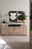 Frontale Ansicht eines modernen Sideboards aus Holz mit schwarzen Akzenten, dekoriert mit Büchern, einer Lampe und einer Pflanze.