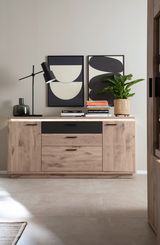 Frontale Ansicht eines modernen Sideboards aus Holz mit schwarzen Akzenten, dekoriert mit Büchern, einer Lampe und einer Pflanze.