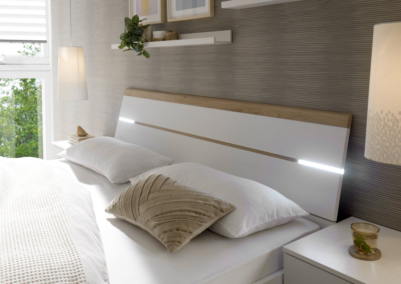 Modernes Schlafzimmer mit einem stilvollen Bett mit Holz- und Weißakzenten, seitlicher Perspektive.