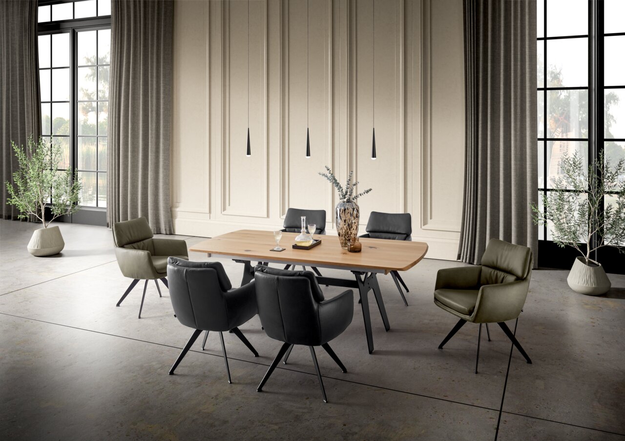 Moderner Essbereich mit einem großen Holztisch und sechs stilvollen Sesseln in einem eleganten Raum mit hohen Fenstern und Vorhängen, seitliche Perspektive.