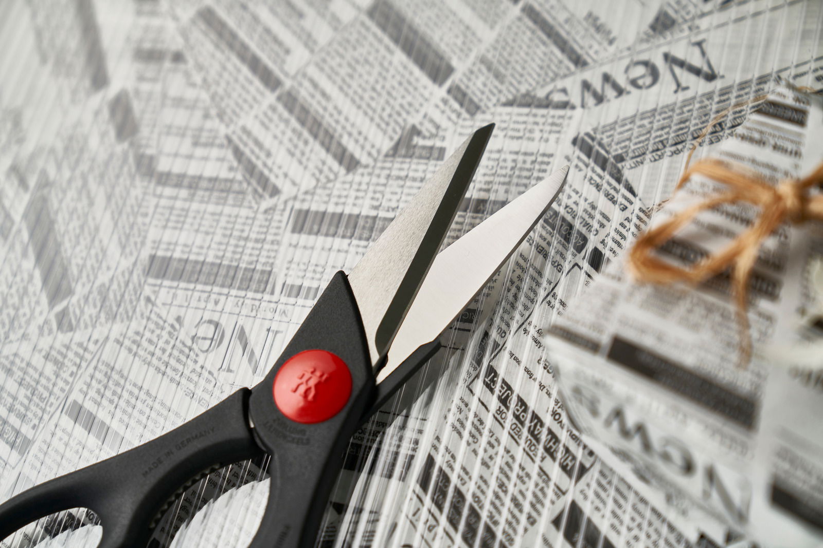 Vielzweckschere mit schwarzem Griff und rotem Akzent, von oben fotografiert auf einem Hintergrund aus Zeitungspapier.