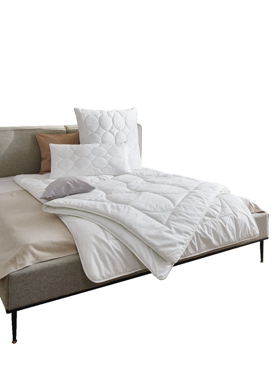 Gemütliches Schlafzimmer mit einem Bett, das mit einer weißen Bettdecke und Kissen ausgestattet ist. Die Perspektive zeigt das Bett von der Seite, mit dekorativen Elementen an der Wand und einem kleinen Beistelltisch.