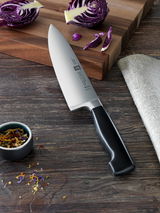 Kochmesser 20cm VIER STERNE auf einem Holztisch, neben einem Schneidebrett mit Rotkohl und Gewürzen, aus der Vogelperspektive.