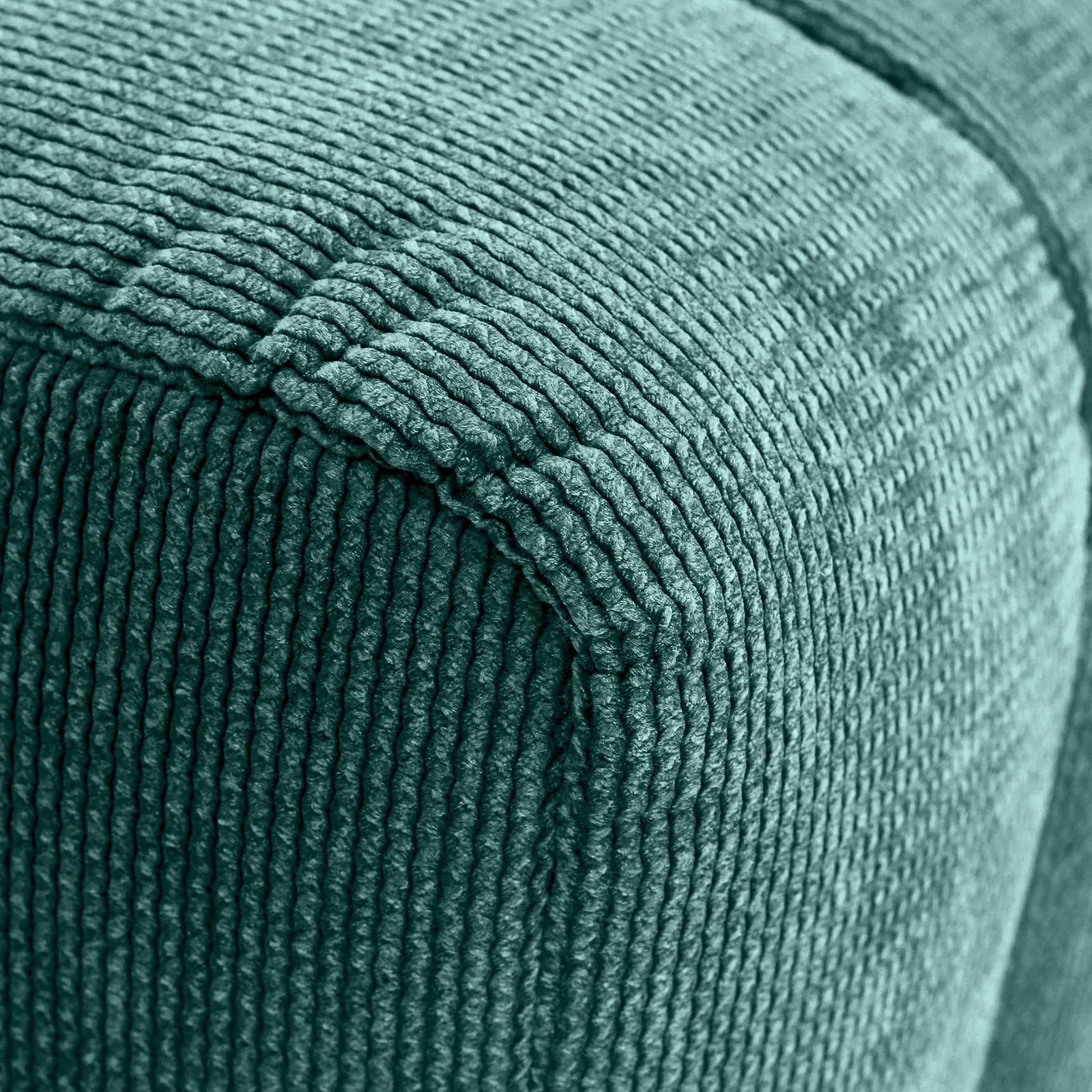 Nahaufnahme eines grünen Hockers mit gerippter Textur, Perspektive von der Ecke.