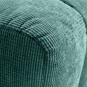 Nahaufnahme eines grünen Hockers mit gerippter Textur, Perspektive von der Ecke.