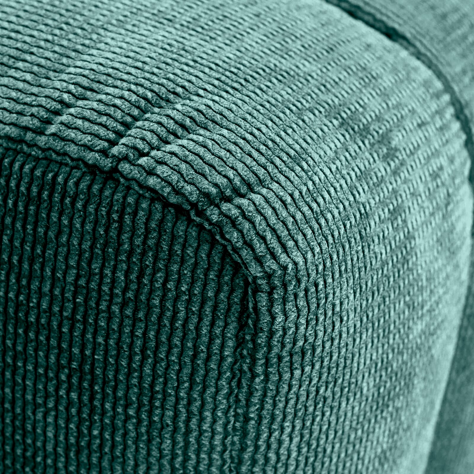 Nahaufnahme eines grünen Hockers mit gerippter Textur, Perspektive von der Ecke.