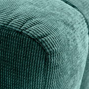 Nahaufnahme eines grünen Hockers mit gerippter Textur, Perspektive von der Ecke.