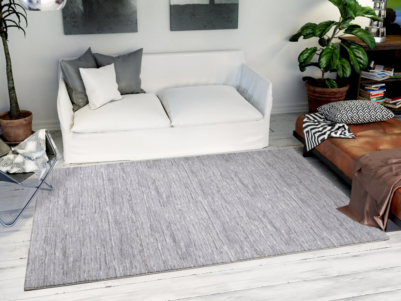 Grauer Uni-Teppich in einem modernen Wohnzimmer mit weißem Sofa, Pflanzen und dekorativen Kissen, aus der Vogelperspektive betrachtet.