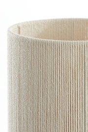 Nahaufnahme eines zylindrischen Lampenschirms aus cremefarbenem, vertikal gewickeltem Garn/Seil vor weißem Hintergrund, Perspektive: leicht von oben und seitlich.