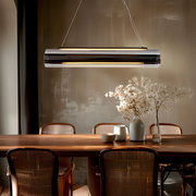 Moderne LED-Hängeleuchte über einem Esstisch, seitliche Perspektive