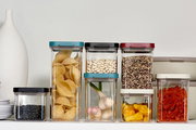 Vorratsdosen Omnia in verschiedenen Größen und Farben, gefüllt mit Lebensmitteln, aus frontaler Perspektive.