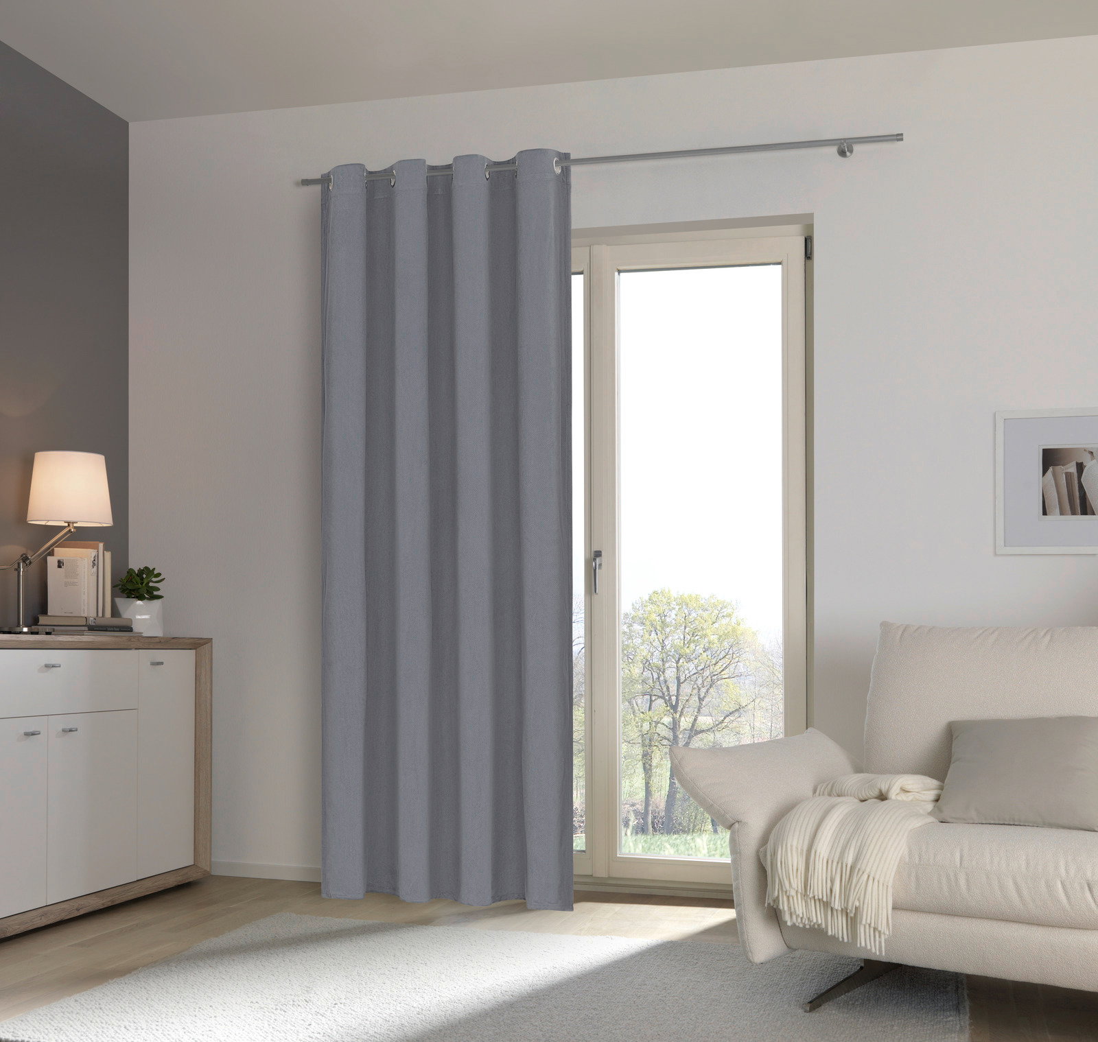 Grauer Ösenschal vor einem Fenster in einem modernen Wohnzimmer, seitliche Perspektive
