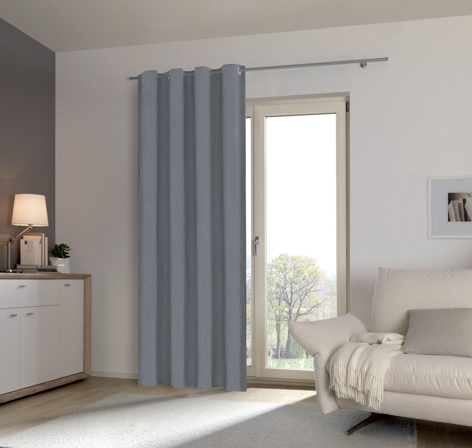 Grijze sjaal met oogjes voor een raam in een moderne woonkamer, zijaanzicht