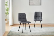Zwei moderne Esszimmerstühle mit grauem Stoffbezug und schwarzem Metallgestell auf hellem Teppich in einem minimalistischen Raum, Perspektive: frontale Ansicht auf Augenhöhe.