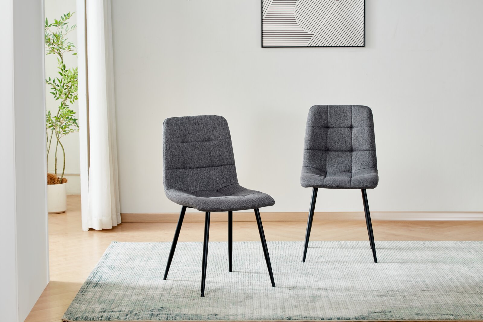 Zwei moderne Esszimmerstühle mit grauem Stoffbezug und schwarzem Metallgestell auf hellem Teppich in einem minimalistischen Raum, Perspektive: frontale Ansicht auf Augenhöhe.