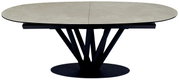 Moderne eettafel met een ovaal, licht blad en een zwart, sculpturaal onderstel, gezien vanaf de zijkant.
