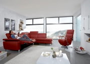 Moderner roter Relaxsessel drehbar in einem hellen Wohnzimmer mit Panoramafenster, seitliche Perspektive