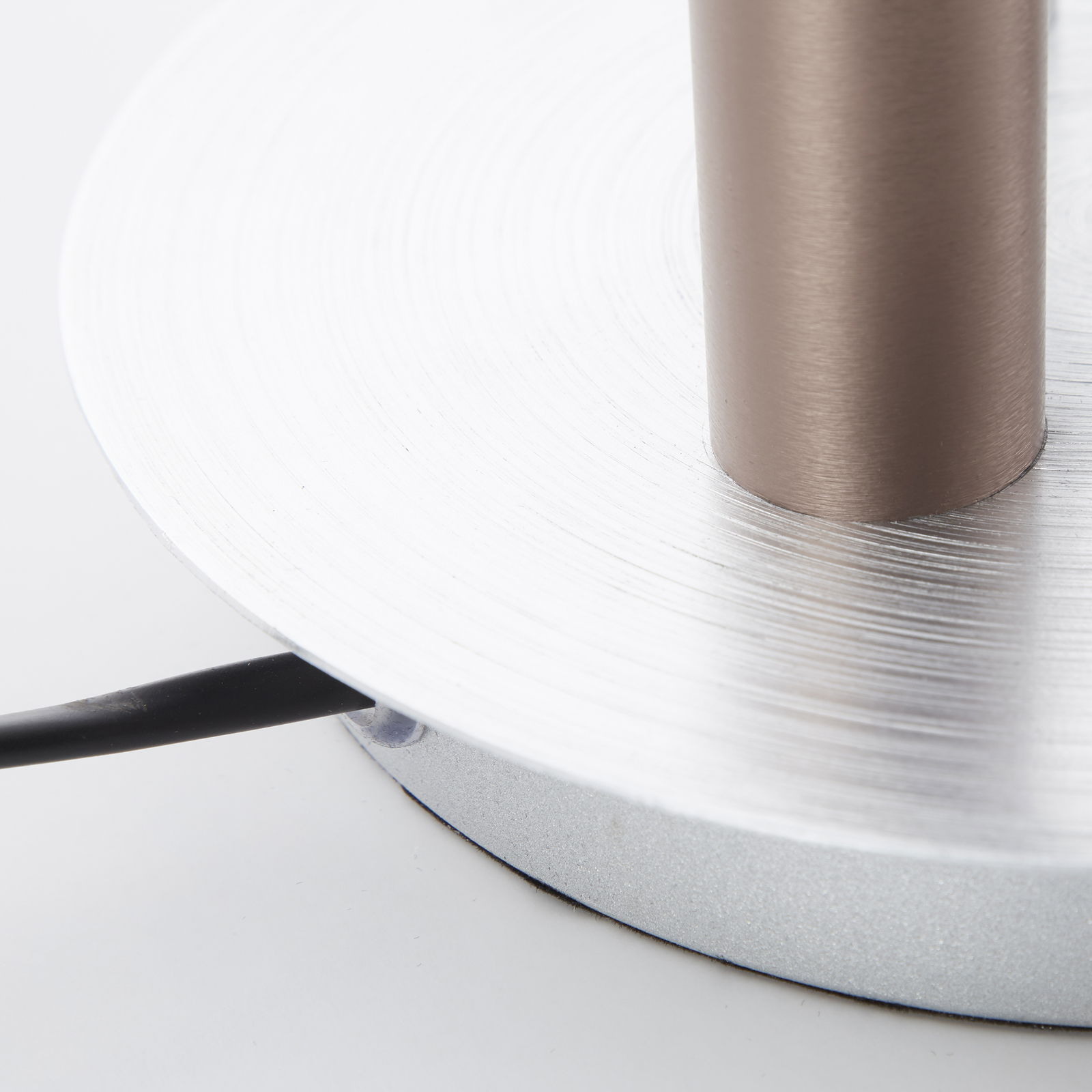 Nahaufnahme der Basis einer Cembalo LED Lampe mit silberner, kreisförmiger Struktur und einem Kabel, das von der Seite herausragt.