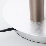 Nahaufnahme der Basis einer Cembalo LED Lampe mit silberner, kreisförmiger Struktur und einem Kabel, das von der Seite herausragt.