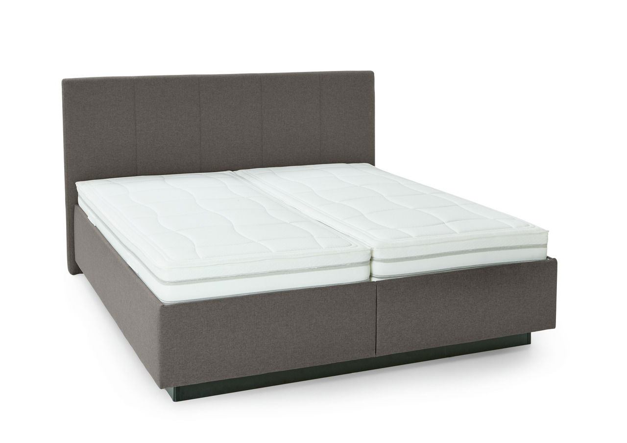 Polsterbett mit grauem Stoffbezug und zwei weißen Matratzen, seitliche Perspektive