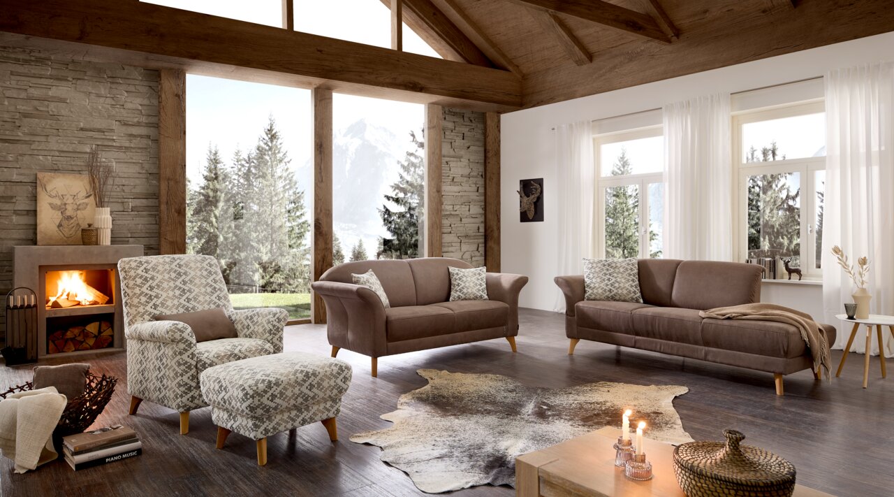 Gezellige woonkamer met een moderne bankstel in een chalet in alpine stijl, met uitzicht op de bergen door grote ramen.