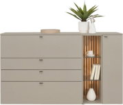 Frontaanzicht van een moderne beige dressoir/commode met vier lades, een deur en een open vitrinekast met glazen planken, houten lattenwand en warme LED-verlichting, gestyled met plant, beeldje, boeken en vaas