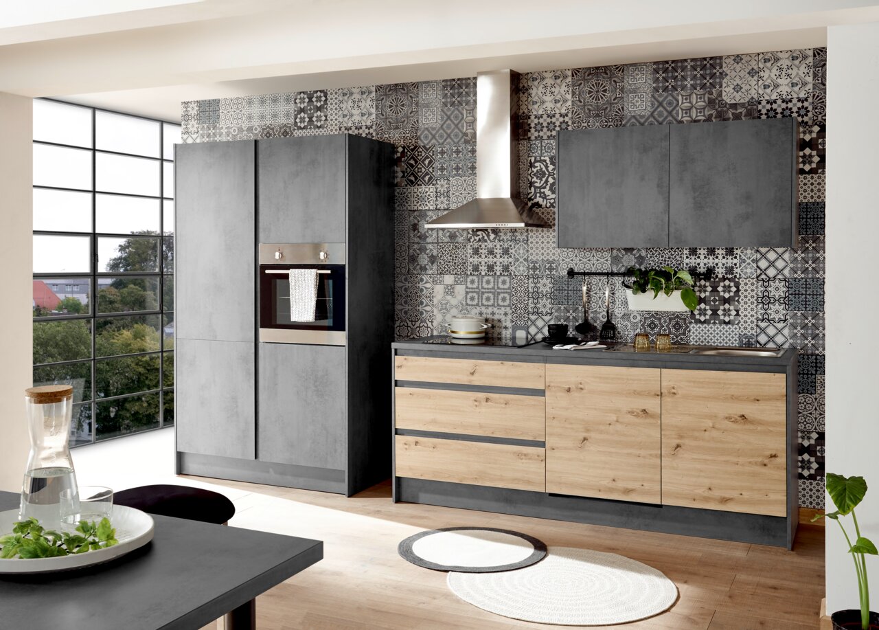 Yourkitchen Küchenblock Basis 335 TROJA Moderne Küche mit grauen und holzfarbenen Fronten, eingebautem Ofen und stilvollen Fliesen im Hintergrund, seitliche Perspektive.