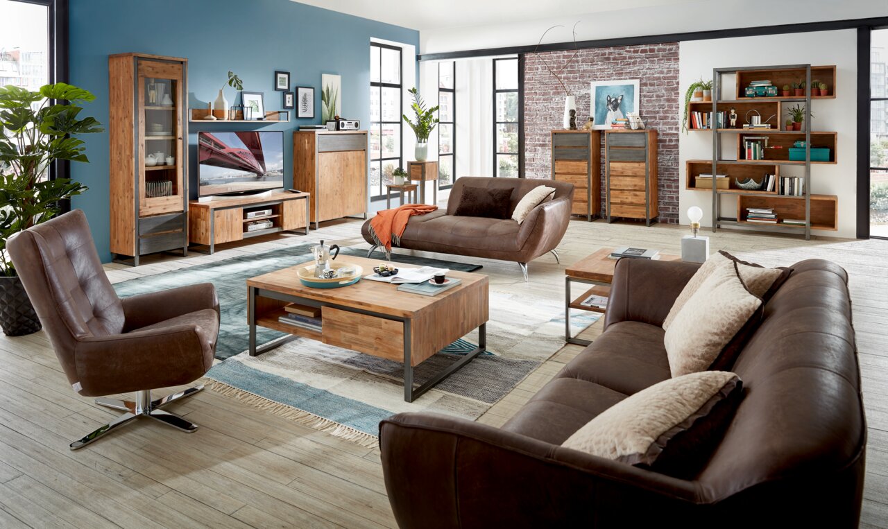 Wohnzimmer mit modernen Holzmöbeln, darunter ein TV-Board, Vitrine, Bücherregal und Couchtisch, aus der Perspektive von vorne betrachtet.
